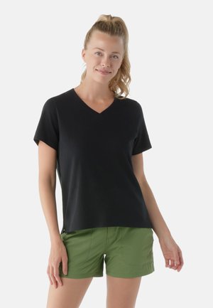 Maglietta nera a maniche corte con scollatura a V realizzata in tessuto morbido, abbinata a pantaloni corti verdi con una texture liscia e una vestibilità su misura.