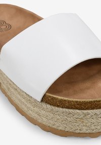 Bílé sandály s širokým páskem, které mají korkovou stélku a platformu obalenou jutou, s texturovaným povrchem na podešvi.