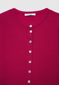 Cardigan côtelé magenta avec un col rond, comportant cinq boutons blancs sur le devant et une étiquette indiquant la taille S.