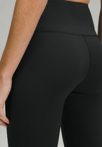 Czarne, prążkowane legginsy z wysokim stanem, o gładkiej teksturze i wzmocnionych szwach.