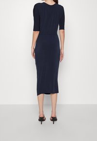 Mörkblå midi-klänning med figurnära siluett, har rundad halsringning och trekvartsärmar, tillverkad av mjukt, stretchigt tyg.