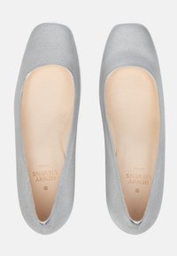 Ballerines argentées avec une texture lisse, un bout carré et un design découpé. L'intérieur est doté d'une doublure beige avec un logo.