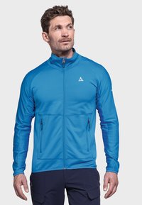 Blaue Zip-Jacke aus strukturiertem Material. Mit seitlichen Taschen und Stehkragen. Das Design umfasst ein kleines Logo auf der Brust.