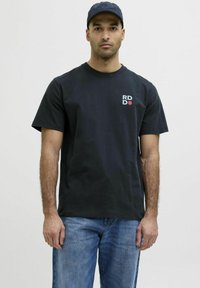 Sort bomulds t-shirt med rund halsudskæring, korte ærmer og et trykt "RD" logo i hvidt og rødt på venstre bryst. Blå denim jeans.