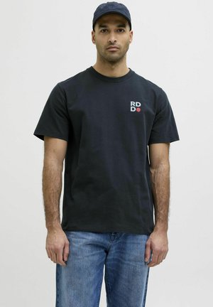 Zwarte katoen T-shirt met een ronde hals, korte mouwen en een gedrukt "RD" logo in wit en rood op de linkerborst. Blauwe spijkerbroek.