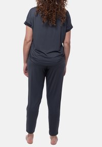 Donkergrijze, loszittende, korte mouwtop met opgerolde manchetten en bijpassende tapered broek, gemaakt van zacht, lichtgewicht materiaal.