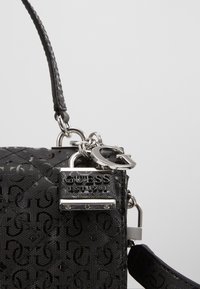Borsa a tracolla sintetica nera con superficie texturizzata e motivo a logo ripetuto, accessori in argento e tracolla removibile.
