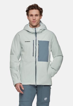 Veste extérieure gris clair avec une poche poitrine gris foncé en contraste. Elle possède une capuche, une fermeture éclair à l'avant et une silhouette épurée.