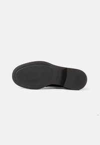 Svart gummisåle med teksturert overflate, med flat design og avrundet tåform. Ingen merkbare mønstre eller accenter synlige.