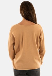 Maglione oversized marrone chiaro con scollo ampio e maniche lunghe. Tessuto morbido e vestibilità rilassata, abbinato a jeans scuri.