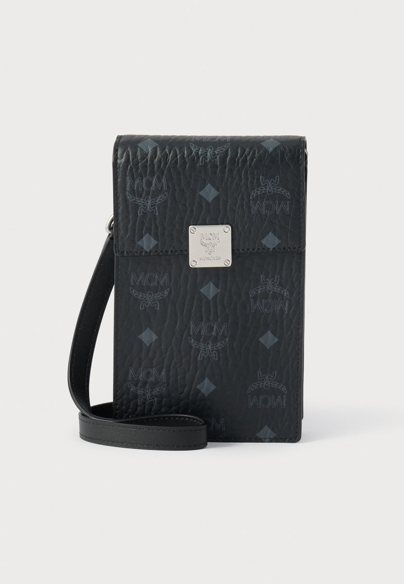 Μαύρο δερμάτινο τσάντα χιαστί με ανάγλυφο λογότυπο MCM, διακοσμητικό μοτίβο ρόμβου, ασημένιες μεταλλικές λεπτομέρειες και αποσπώμενο λουρί. Συμπαγής, ορθογώνιος σχεδιασμός.