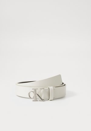 Cintura in pelle bianca con una texture liscia, dotata di una fibbia in tono argentato con le iniziali "CK". Lunghezza regolabile con un design elegante.