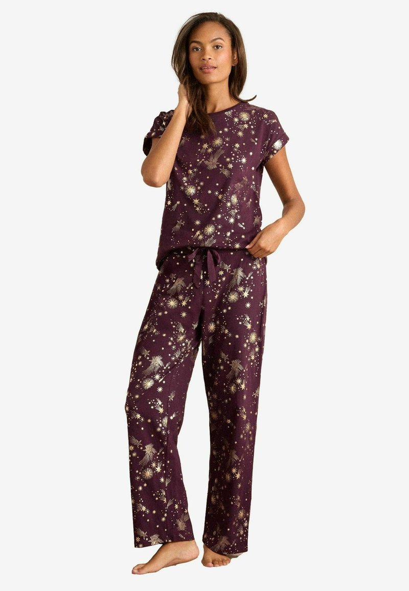 Conjunto de pijama para mujer en púrpura profundo con patrones de explosiones doradas. Parte superior de manga corta y pantalones largos y holgados con cintura ajustable.