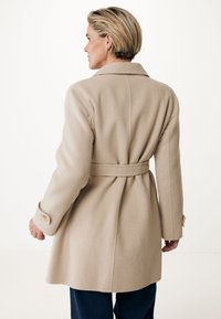 Abrigo de mezcla de lana beige con cintura ajustada, cuello con muescas y puños abotonados, que presenta un corte entallado y una textura suave.