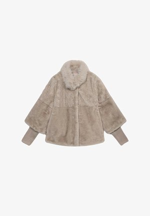 Jas van kunstbont in lichtbeige met een zachte, pluche textuur, voorzien van een brede kraag en geribbelde gebreide manchetten. Het ontwerp is hoekig en kort.