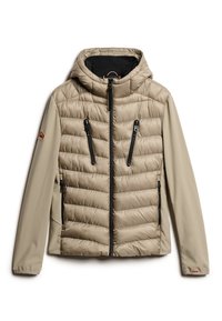 Beige pufferjakke med quiltet tekstur, en hætte og sorte lynlåslommer. Har blødt stof og et broderet brandlogo på ærmet.