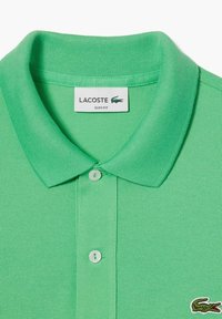 Zöld Lacoste slim fit póló, bordás gallérral, két gombos lezárással és egy kis hímzett krokodil logóval. Strukturált anyag.