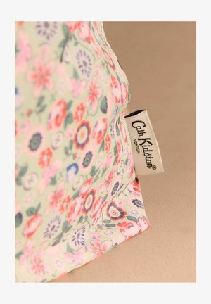 Zaļš auduma maisiņš ar ziedu rakstu, kurā ir daudzkrāsainas ziedi. Komplektā ir melns un balts uzraksts ar tekstu "Cath Kidston London".