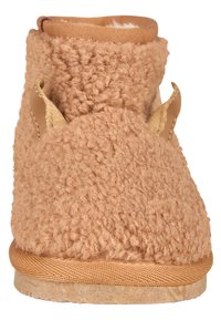 Beiger, flauschiger Hausschuh mit einer weichen, texturierten Außenseite, elastischem Kragen und einer beigen Gummisohle. Verfügt über ein kurzes, rundes Design für zusätzlichen Komfort.