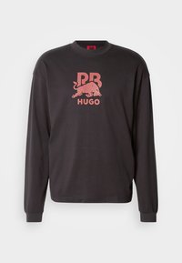 Felpa nera a maniche lunghe con collo rotondo. Presenta un logo grafico rosso con un toro e il testo "HUGO" al centro. Materiale in morbido cotone.
