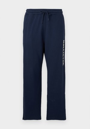 Pantalones de chándal azul marino con cintura elástica y cordón, piernas rectas y "Hollister" impreso verticalmente en el lado derecho.