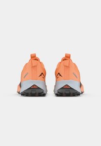 Buty do biegania w terenie w jaskrawym pomarańczowym kolorze z szarymi akcentami, z wytrzymałą tkaniną na cholewce, uchwytami do zakupu oraz solidną czarną podeszwą dla lepszej przyczepności.