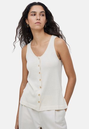 Top de punto de color crema claro con cuello en V, que presenta seis botones de madera en el frente y un dobladillo recto. Diseño minimalista, estilo sin mangas.