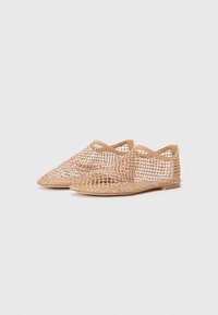 Chaussures en mesh couleur nude, légères, avec un bout pointu et un design ouvert. Matériau texturé et flexible, sans matériel visible.