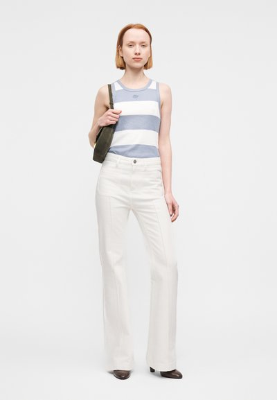 Άσπρο παντελόνι με φαρδιά μπατζάκια συνδυασμένο με μπλε και λευκή ριγέ αμάνικη μπλούζα. Το μοντέλο κρατά μια μικρή πράσινη τσάντα. Λείες υφές, καθημερινό σχέδιο.