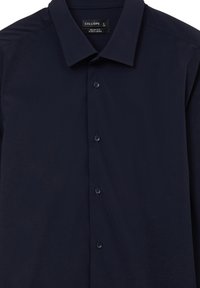 Camicia slim-fit blu navy con colletto a punte, chiusura a bottoni e tessuto facile da stirare. Morbido al tatto, presenta sei bottoni e dettagli minimi.