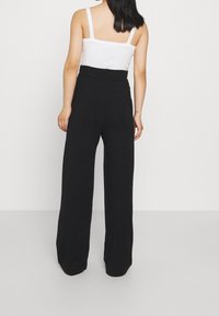 Black wide-leg pants with a high waistband, made from a soft fabric. Smooth texture, casual design without visible patterns or hardware.