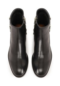 Botas de tobillo de cuero negro con un acabado liso, que cuentan con un cierre lateral y un hardware decorativo en tono dorado a lo largo de la línea del cierre.