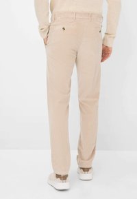 Pantaloni in corduroy beige con vestibilità dritta, due tasche sul retro e una superficie leggermente strutturata. Abbinati a sneakers bianche e marroni.