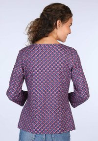 Langärmliges Oberteil aus navyblauem Stoff mit einem pink-weißen Paisleymuster. Es hat einen runden Halsausschnitt und einen leicht ausgestellten Saum.