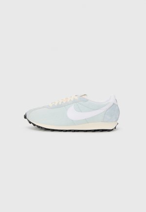 Light blue athletic shoes with a white swoosh, textured fabric, cream accents, and black rubber outsole. Features a lace-up design.