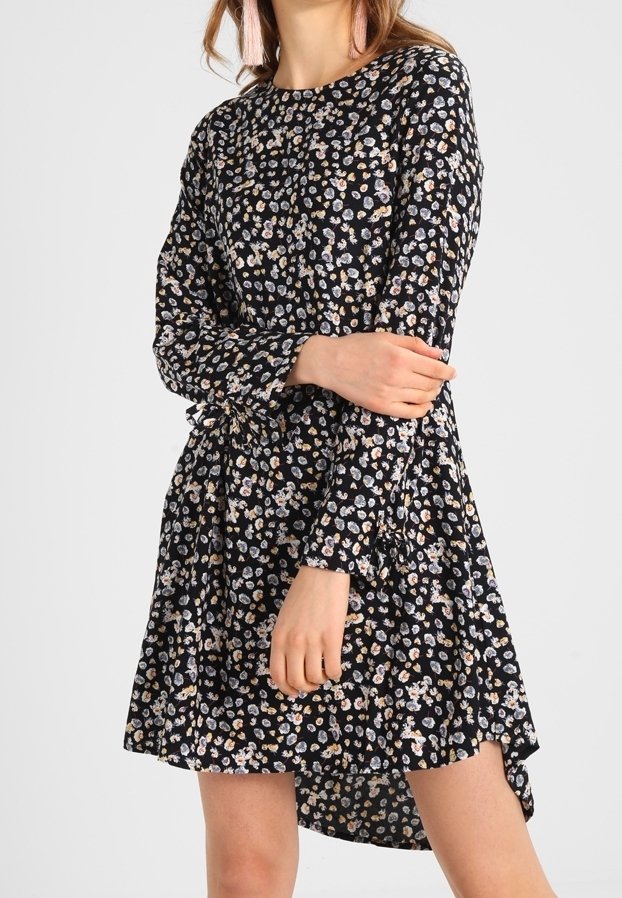 Robe noire à fleurs avec manches longues, dotée d'un ourlet à volants à plusieurs niveaux, d'un petit motif floral multicolore et d'un col rond.