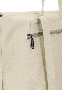 Borsa in pelle beige con superficie testurizzata, dotata di una cerniera argento e un'etichetta con logo attaccata. Le spalline sono lisce e robuste.