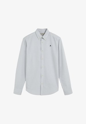 Chemise à manches longues rayée bleu clair et blanche, avec un col boutonné, des boutons sur le devant et un petit logo de crâne noir sur la poitrine.