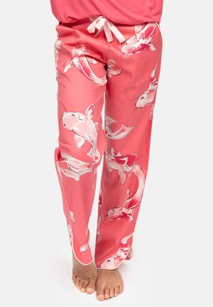 Rosa Pyjamahose mit weißen und roten Koi-Fisch-Mustern, barfuß getragen, Vorderansicht der Beine und Füße vor weißem Hintergrund.