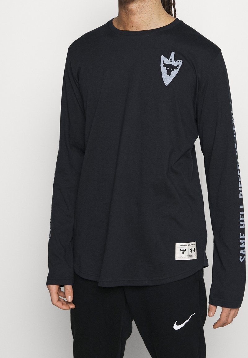 Czarna koszula z długim rękawem, wykonana z bawełny, z okrągłym dekoltem. Posiada graficzne logo na klatce piersiowej oraz napis wzdłuż rękawa.