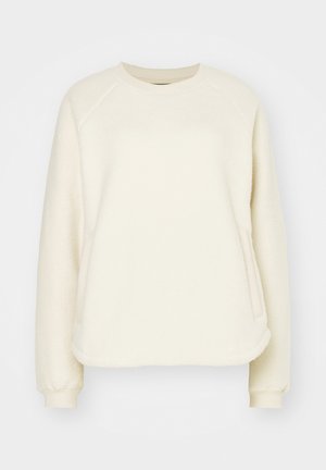 Kreminės spalvos pūkuota džemperis su ilgomis raglan rankovėmis, apvaliu iškirpimu ir šoninėmis kišenėmis. Minkšta tekstūra su gaubtu apdailos kraštu.