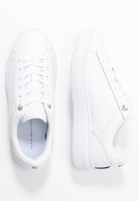 Białe skórzane sneakersy z okrągłym czubkiem, sznurowanym zapięciem, teksturowaną podeszwą i srebrnymi akcentami. Wnętrze wykończone niebieską siateczką.