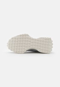 Suela de zapato con un patrón texturizado blanco que presenta pequeños agarres circulares, mostrando un diseño ligeramente elevado y contorneado.