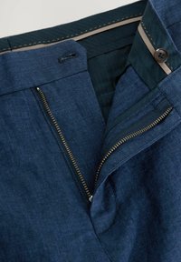 Pantalons bleu marine en tissu texturé, dotés d'une fermeture éclair dissimulée, d'un bouton de fermeture et d'une doublure intérieure beige avec des coutures contrastantes.