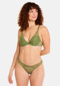 Ensemble de lingerie en dentelle verte comprenant un bralette triangle avec des motifs floraux et un thong assorti. Tissu léger avec des bretelles ajustables.