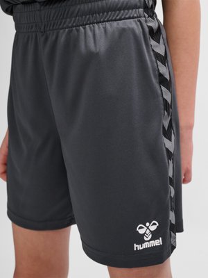 Shorts de sport noirs avec une taille élastique et des bandes latérales à motif chevron, avec un logo Hummel blanc près de l'ourlet.
