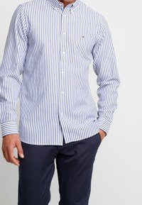 Blauwe en witte verticale gestreepte overhemd met knopen, gemaakt van katoen. Beschikt over een klein logo, een kraag en lange mouwen met knopenmanchetten.