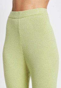 Geribbelde leggings in lichtgroen, met een hoge tailleband en een gestructureerde stof. Zijsplit zichtbaar, wat het aansluitende ontwerp benadrukt.
