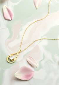 Gul vedhængsnor med et tåreformet design, der har en central klar sten og små omgivende krystaller på en delikat kæde.