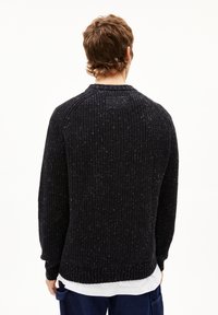 Schwarzer, gerippter Strickpullover mit einer strukturierten Oberfläche, langen Ärmeln und einem runden Ausschnitt. Dezente, weiß gesprenkelte Details im ganzen Design.